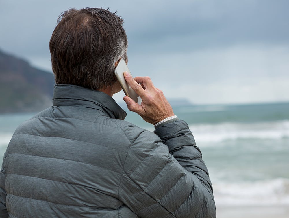 Man near the ocean calling on his mobile phone